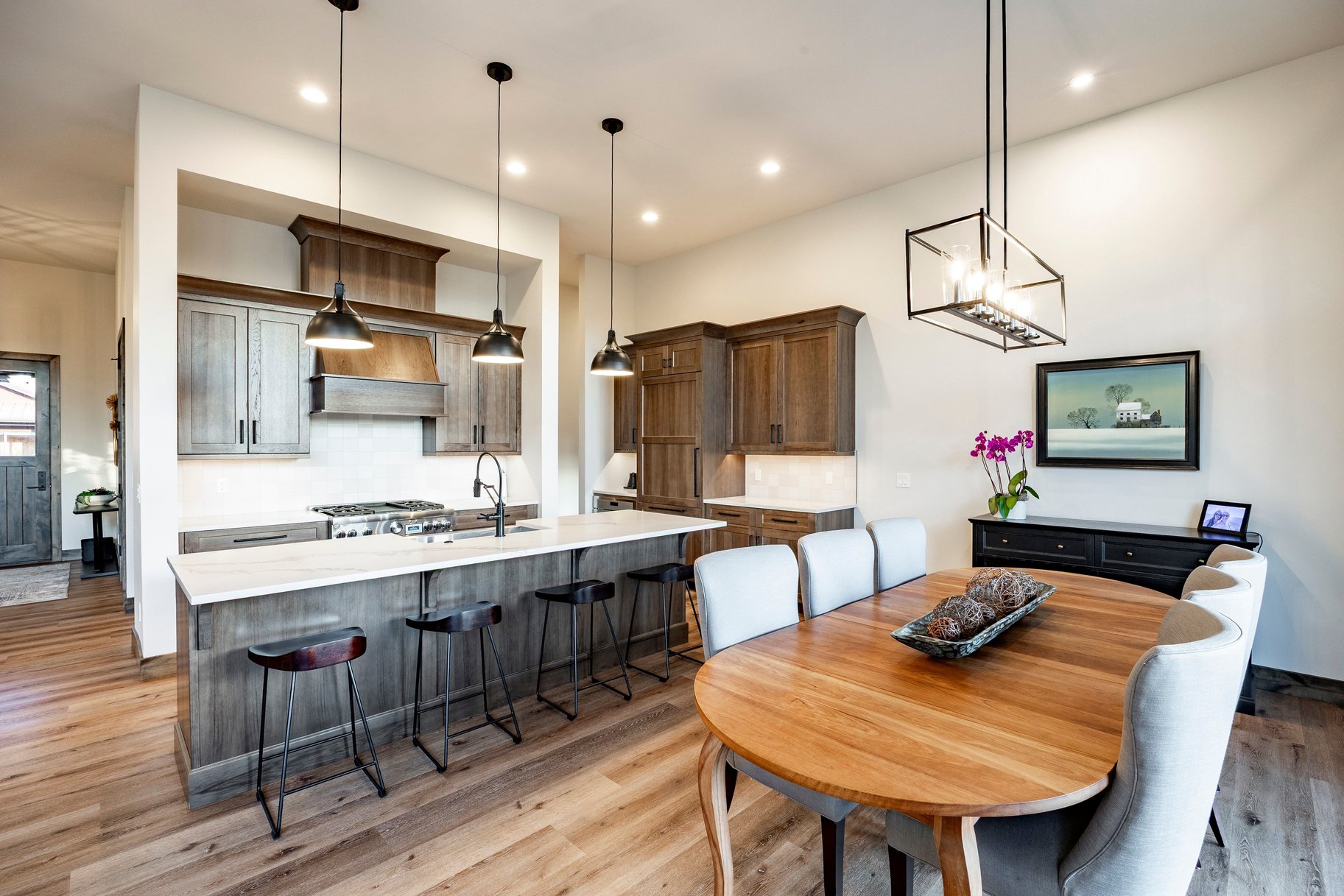 Open-concept kitchen and dining area featuring wood-finish flooring, recessed lighting, and modern fixtures