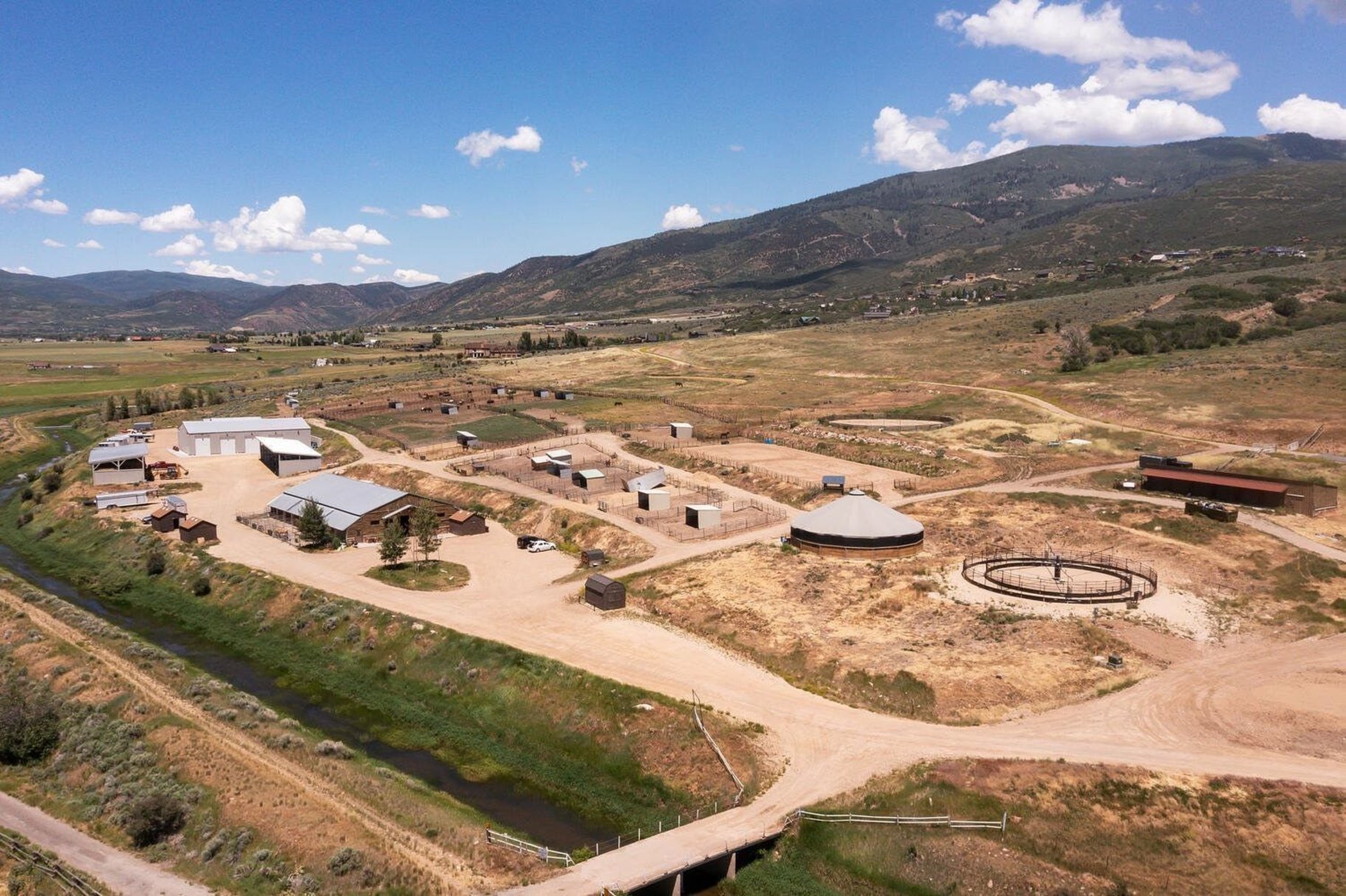 Expansive rural property featuring multiple structures, open land, and mountain backdrops