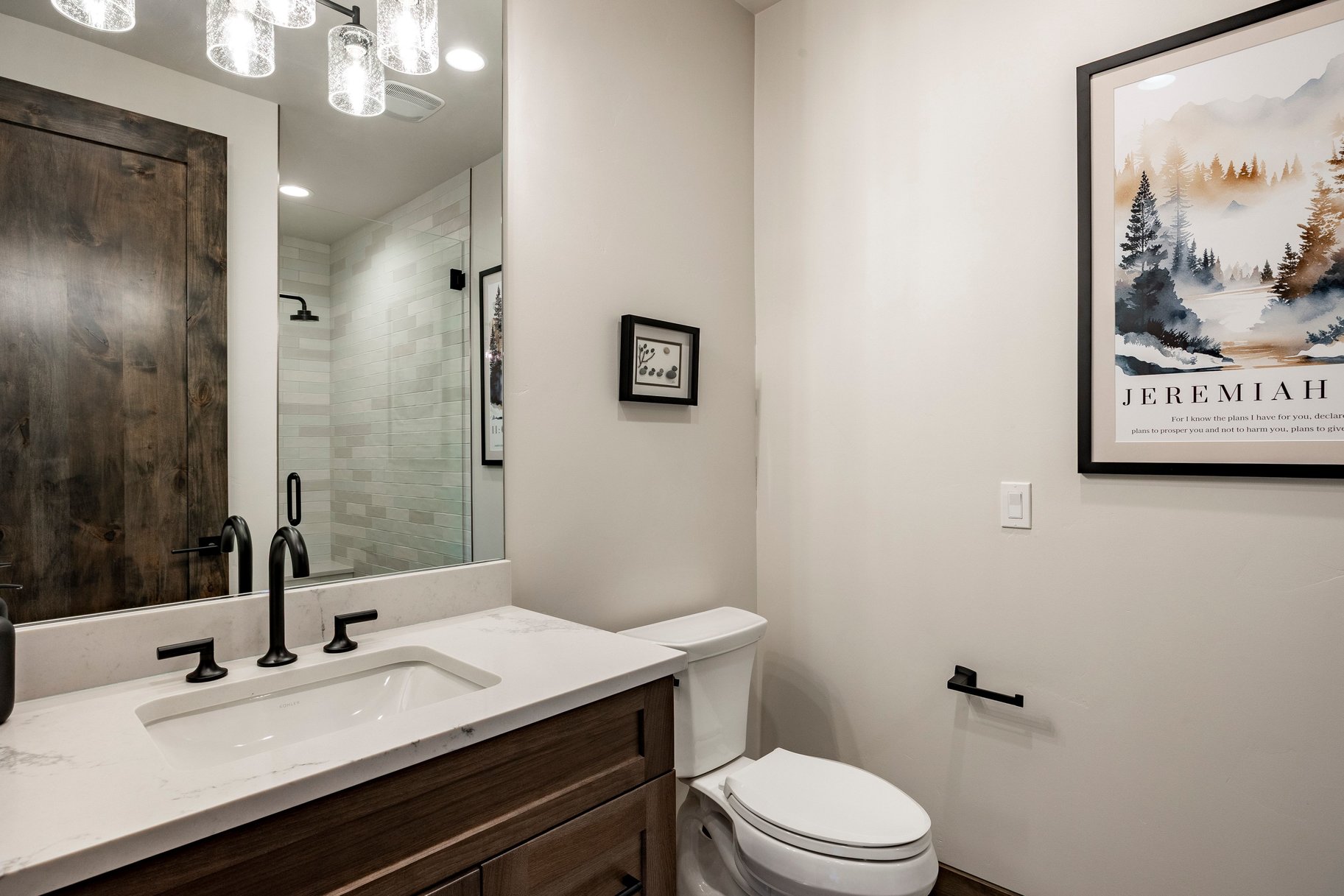 Bathroom featuring a wood-finish vanity with a white countertop, matte black faucet, and a large mirror