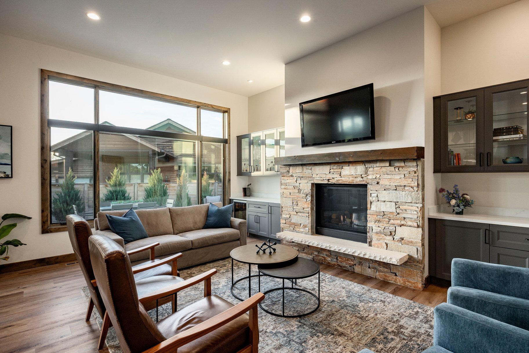 Spacious living area featuring a stacked stone fireplace with a substantial wood mantel, a stone hearth, and integrated media space