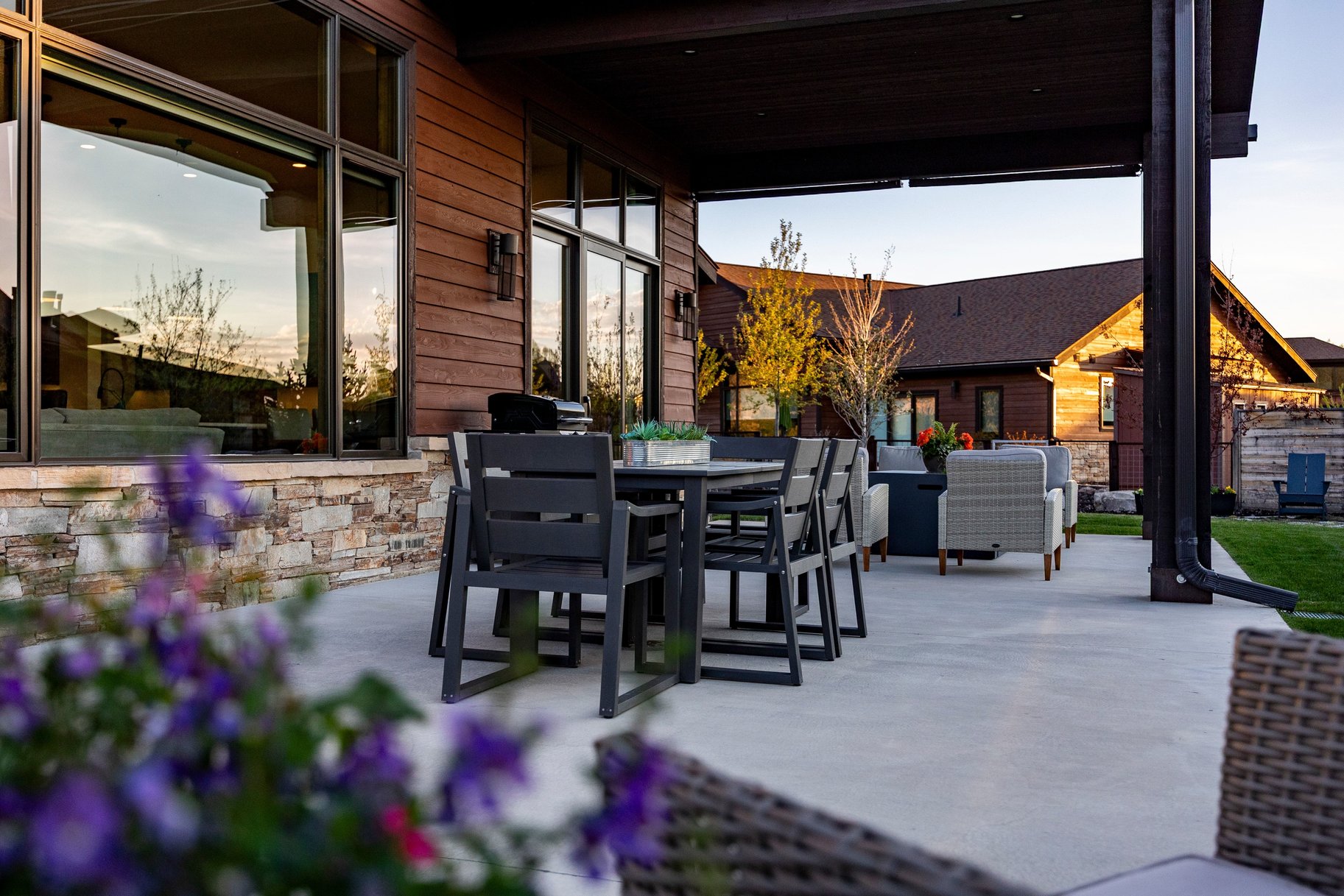 Spacious outdoor patio featuring a concrete surface, a stacked stone base, and a brown wood-paneled exterior