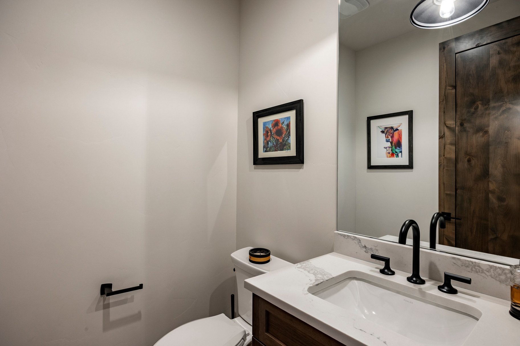Bathroom featuring a wood-finish vanity with a white countertop and integrated sink, matte black faucet, and a large wall-mounted mirror