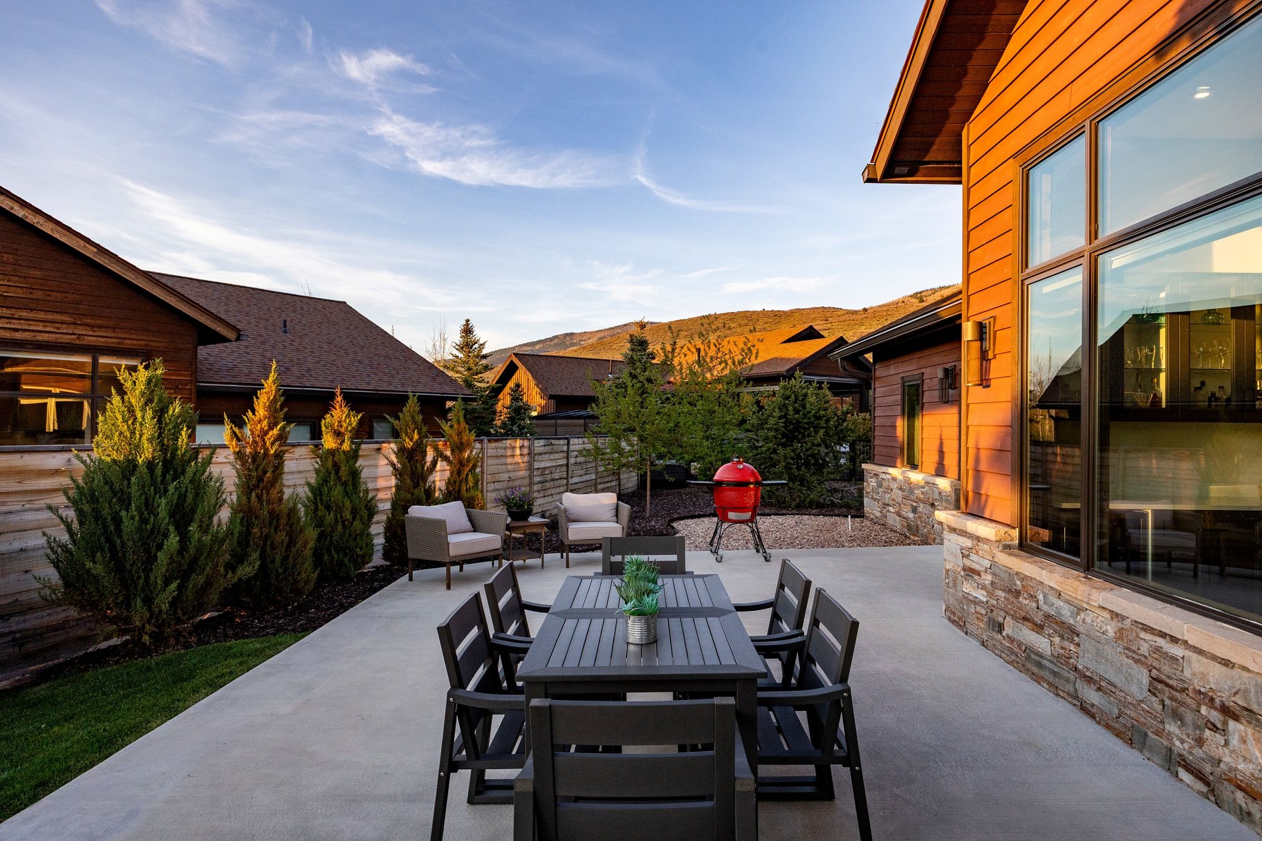 Spacious outdoor patio featuring a concrete surface, wood siding, stone veneer accents, and large picture windows