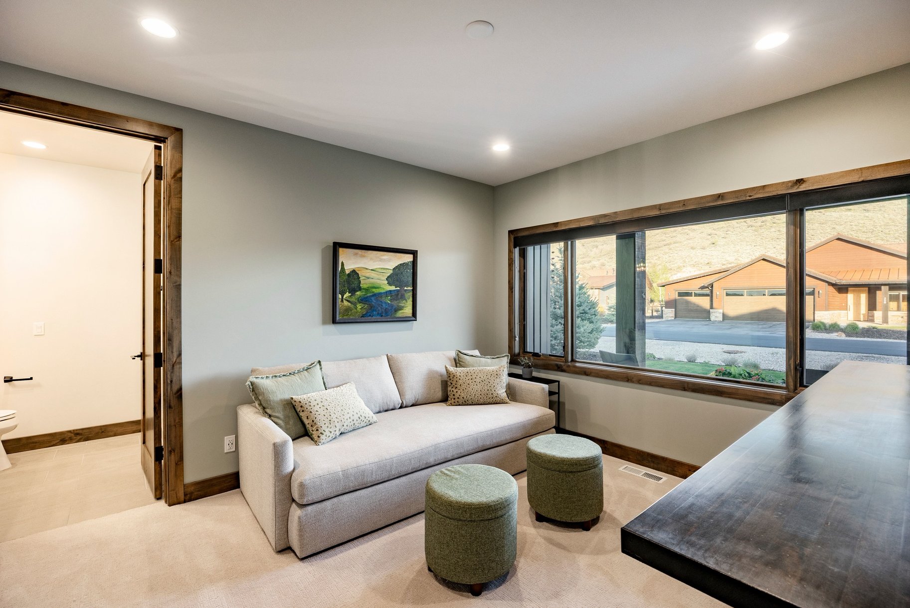 Expansive multi-pane window with dark wood framing, recessed lighting, and light-colored wall paint