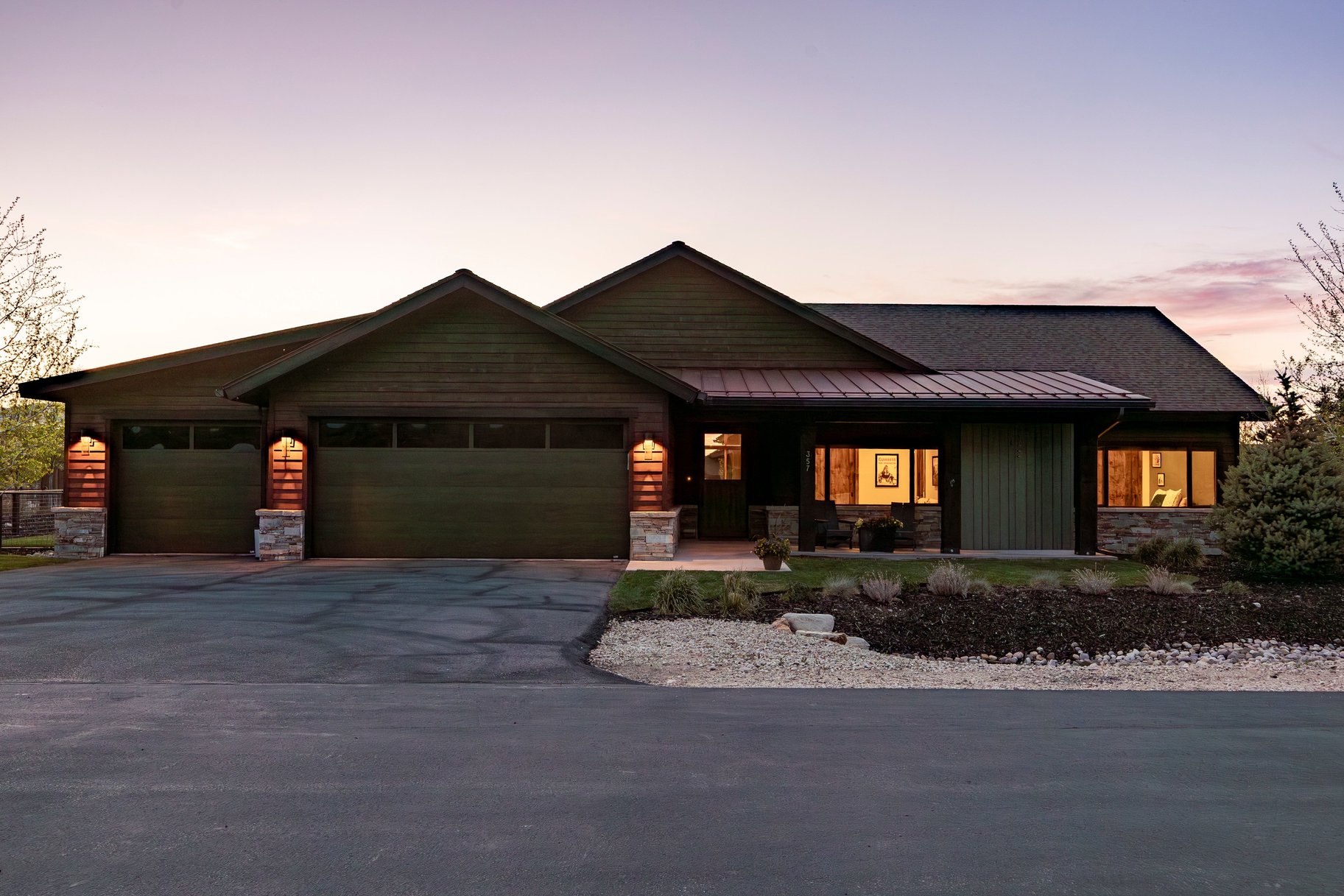 Ranch-style residence featuring a dark wood-paneled exterior, stone accents, and a covered entry