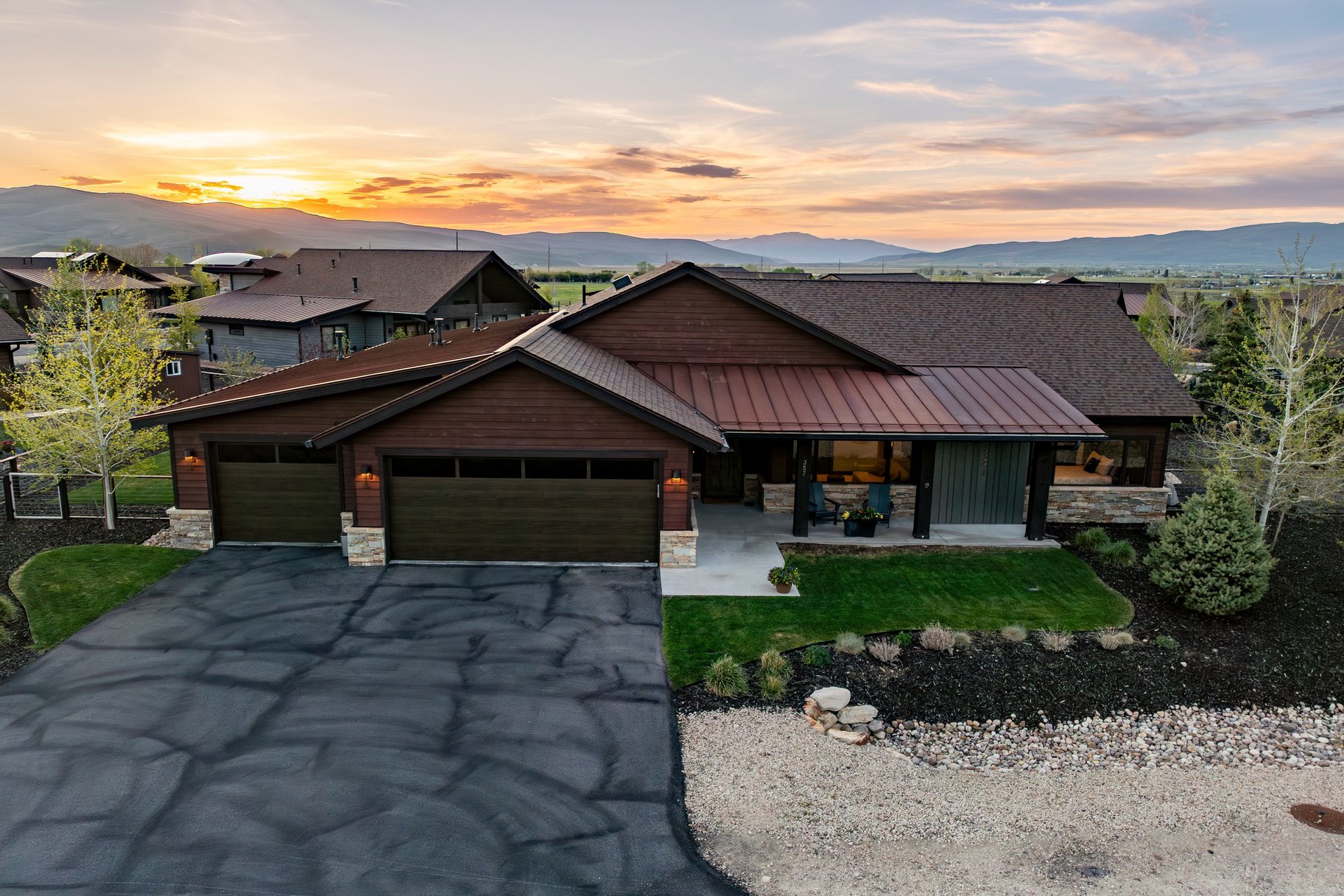 Contemporary exterior featuring rich wood siding, stone accents, a covered entry, and an attached two-car garage