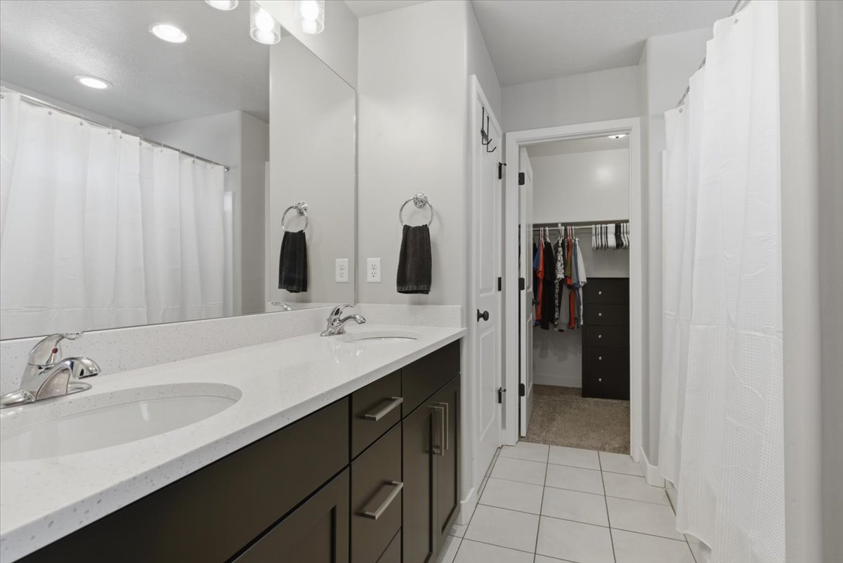 Bathroom featuring a double vanity with stone countertops, integrated sinks, and dark wood-finish cabinetry