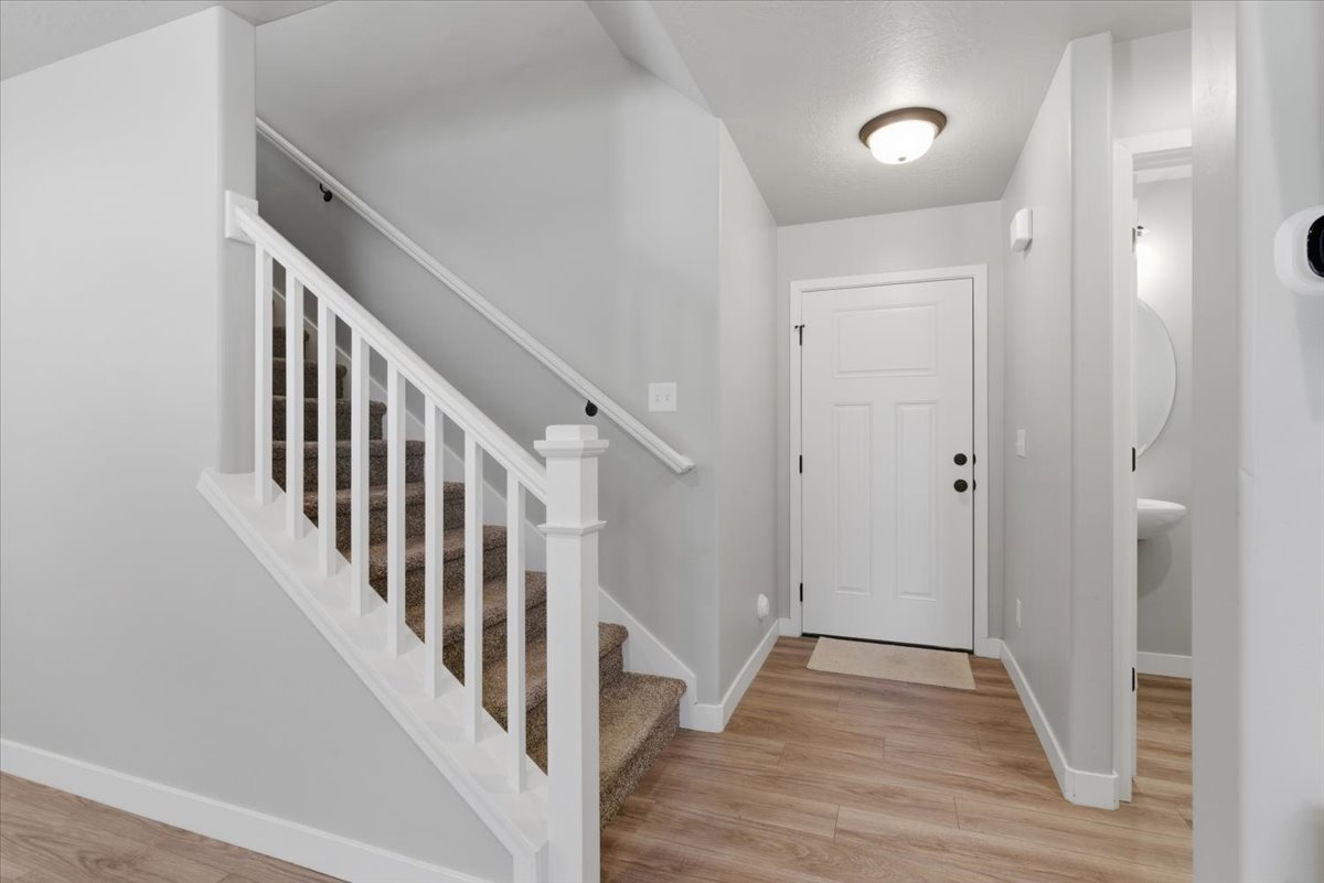 Entryway featuring wood-finish flooring and a staircase with white balusters and carpeted treads