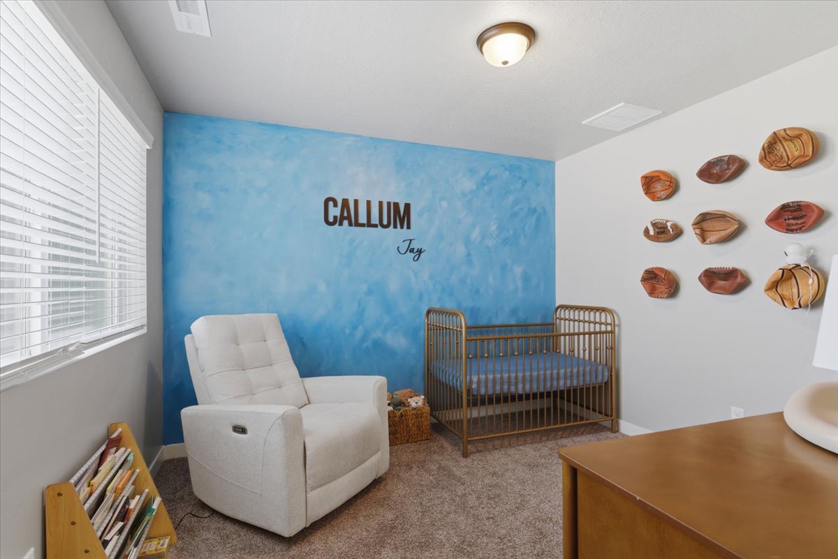 Room featuring a textured blue accent wall, neutral carpeting, and a ceiling-mounted light fixture