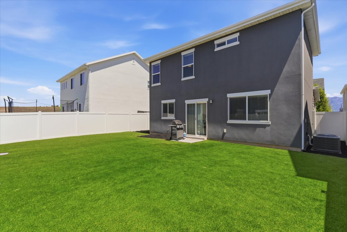 Expansive green lawn with a white vinyl fence encompassing the property