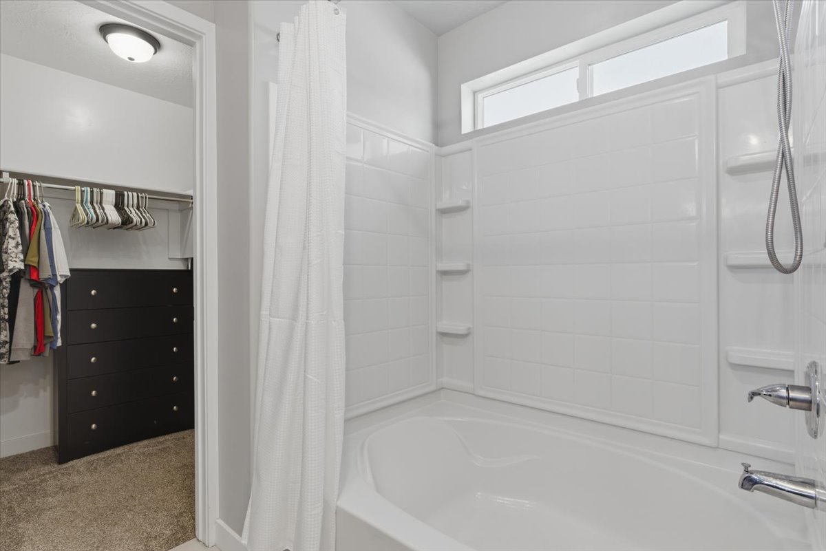 White bathtub with built-in shelving and an overhead transom window