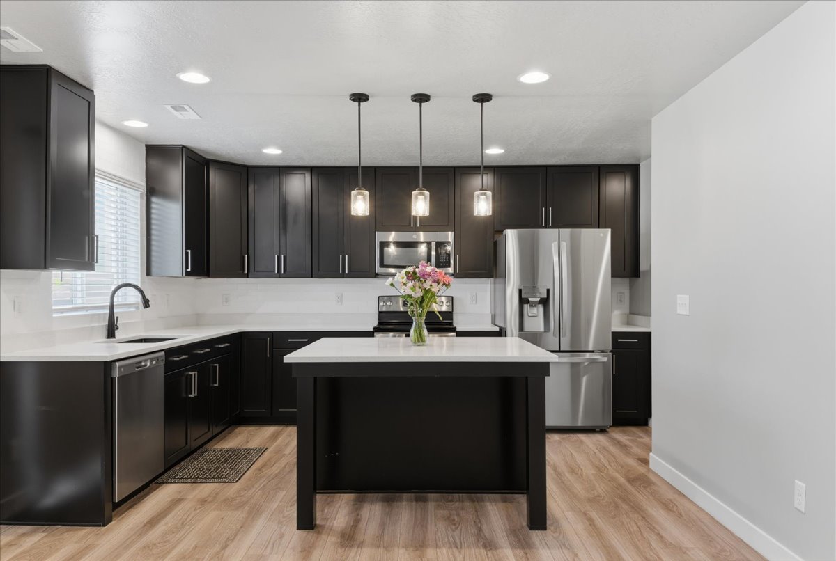 Contemporary kitchen featuring dark cabinetry, light countertops, wood-finish flooring, and recessed lighting