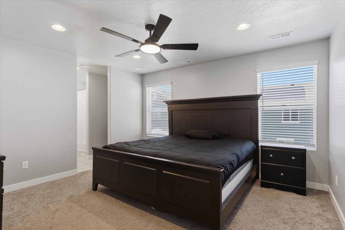Carpeted bedroom featuring recessed lighting, a ceiling fan with integrated light, and two windows with blinds
