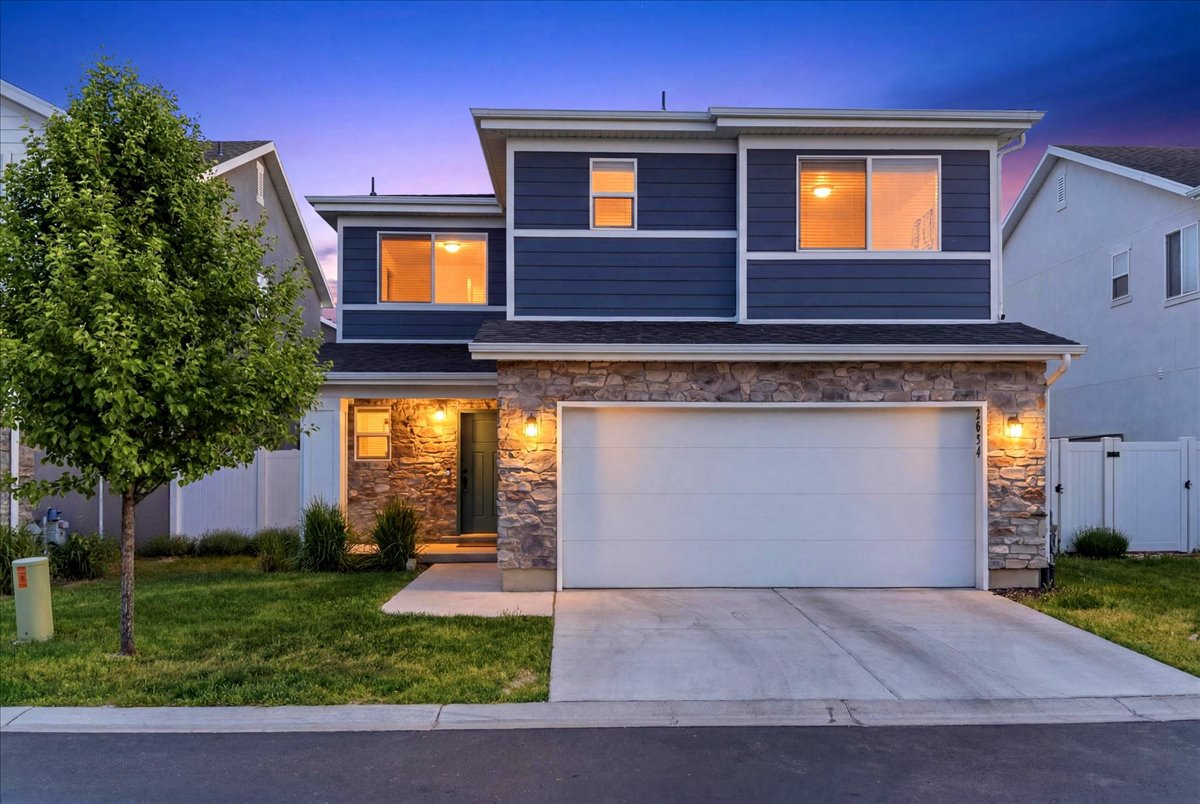 Modern two-story residence featuring a striking blue siding facade and a stone accent lower level