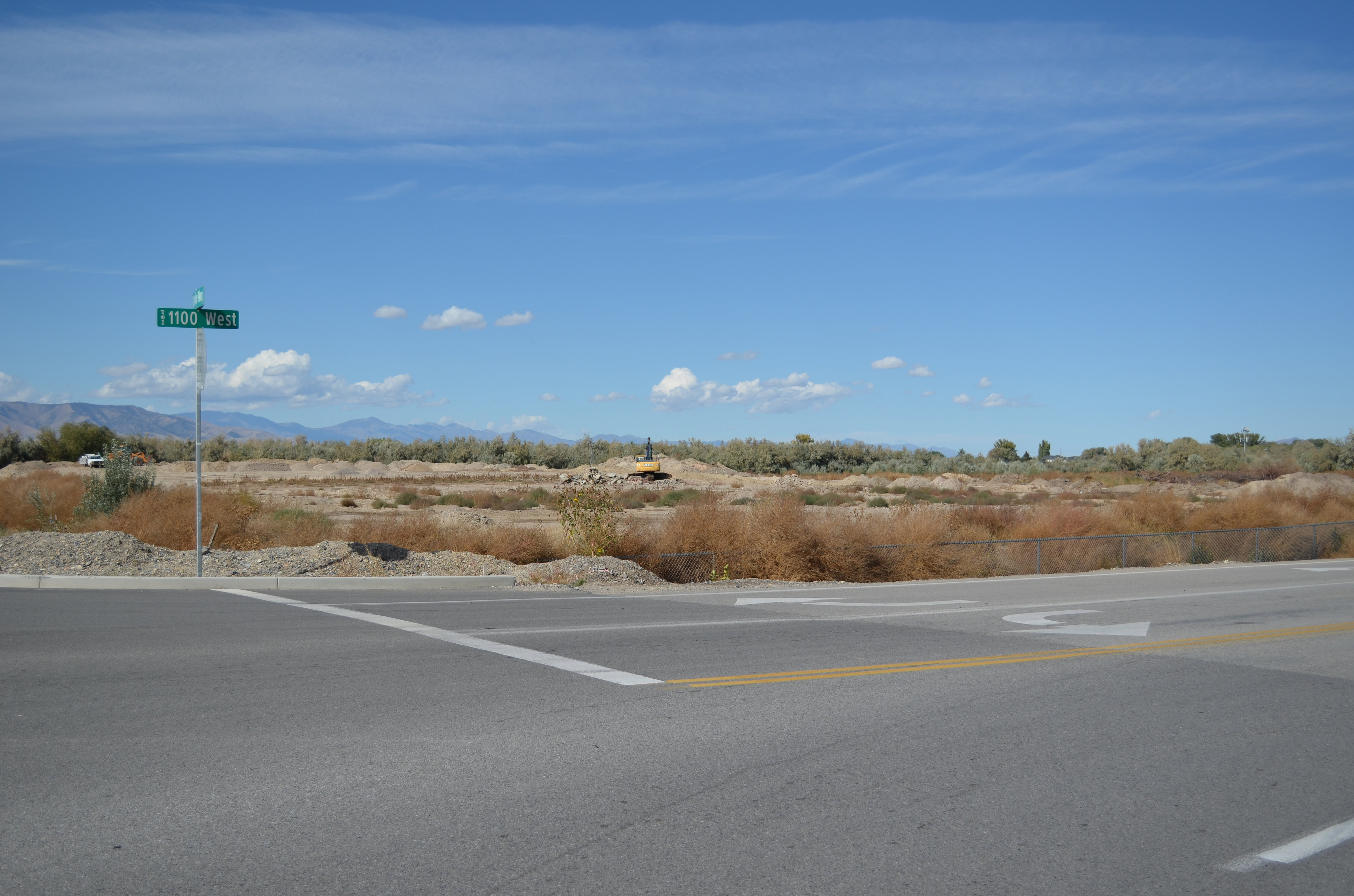 Expansive undeveloped land featuring natural desert vegetation, a clear blue sky, and distant mountains