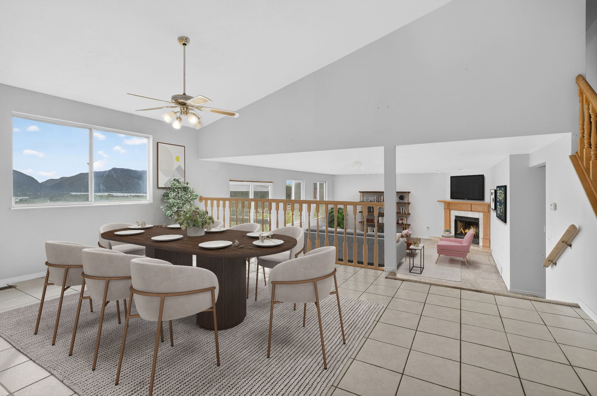 Vaulted ceiling dining area featuring a ceiling fan with integrated lighting, large window with a mountain backdrop, ceramic tile flooring, and an open railing overlooking a lower-level living space