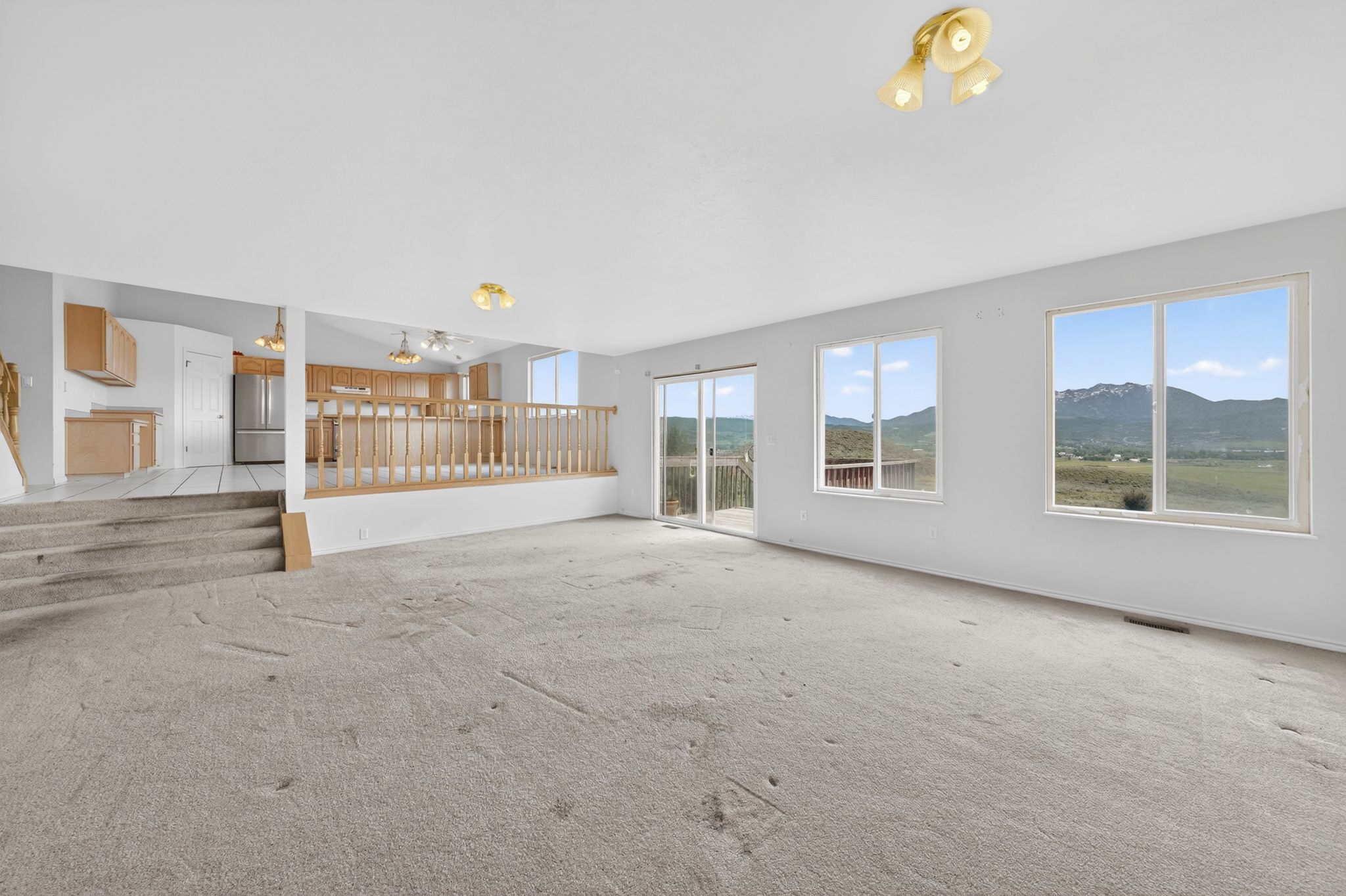 Spacious living area with carpet flooring and ample natural light from multiple windows