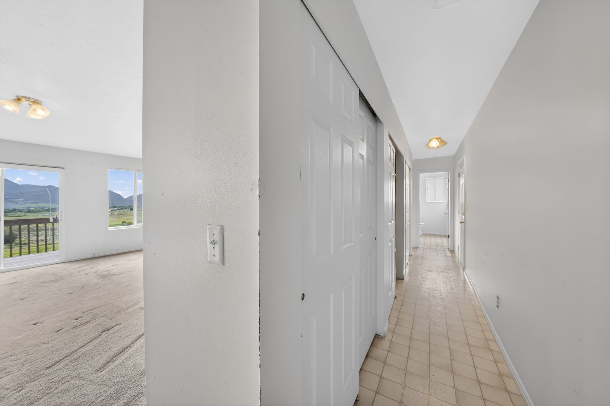 Hallway featuring textured flooring, flush-mount lighting, and bi-fold closet doors
