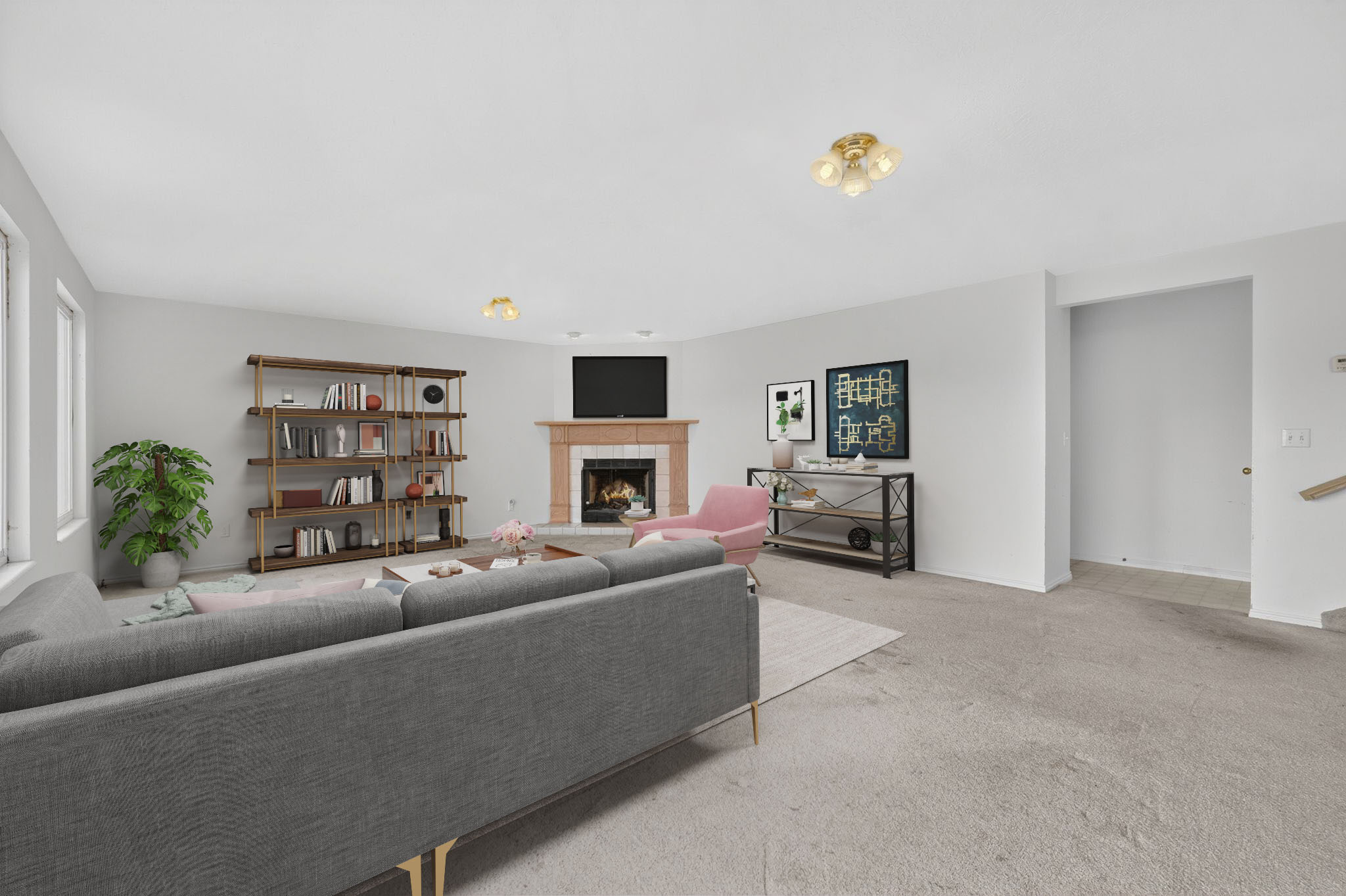 Spacious living area featuring a central fireplace with a light-toned mantel, light-colored walls, and neutral carpeting