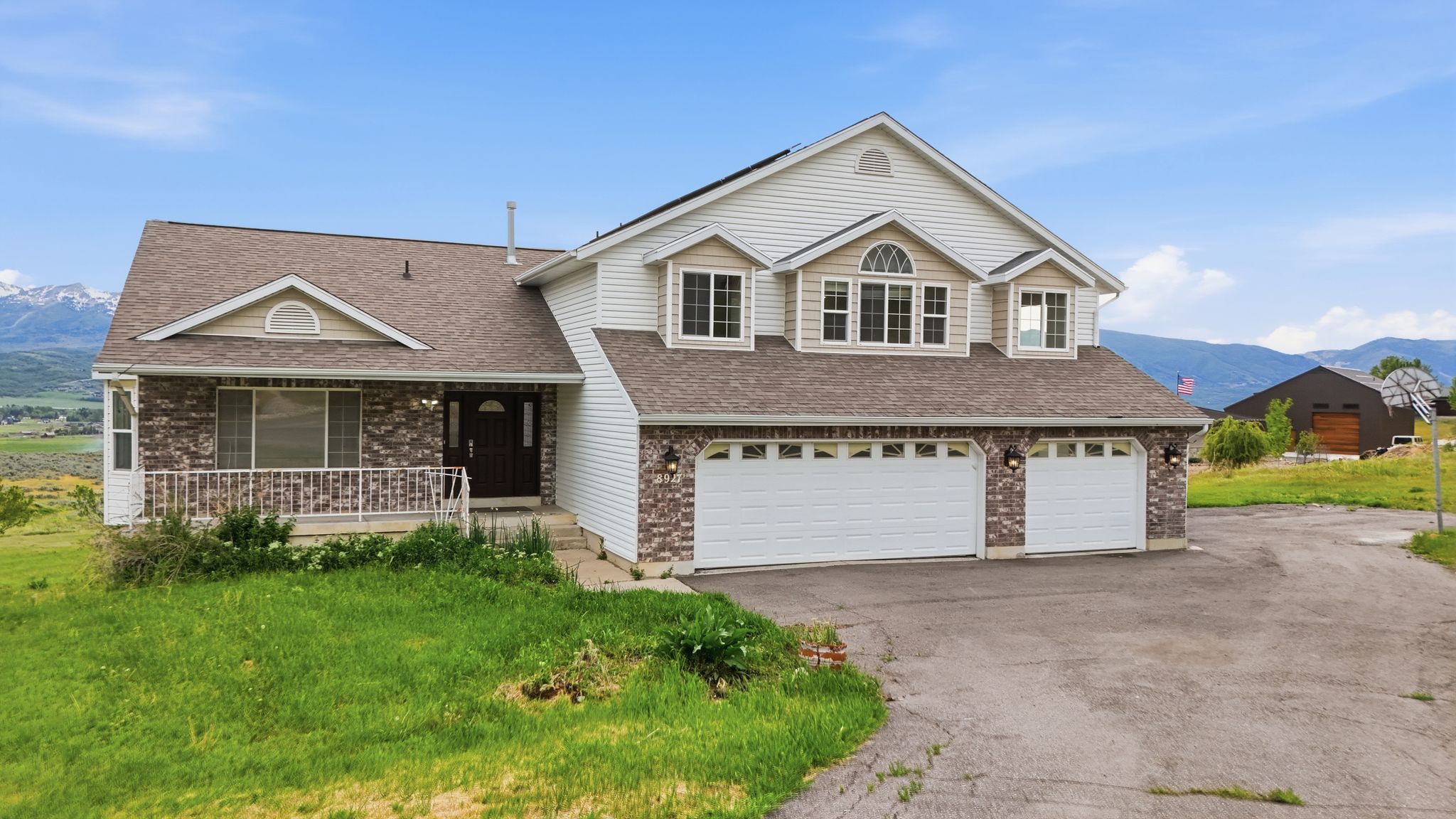 Two-story residence featuring a combination of brick and siding, a covered front porch with railings, and an attached three-car garage