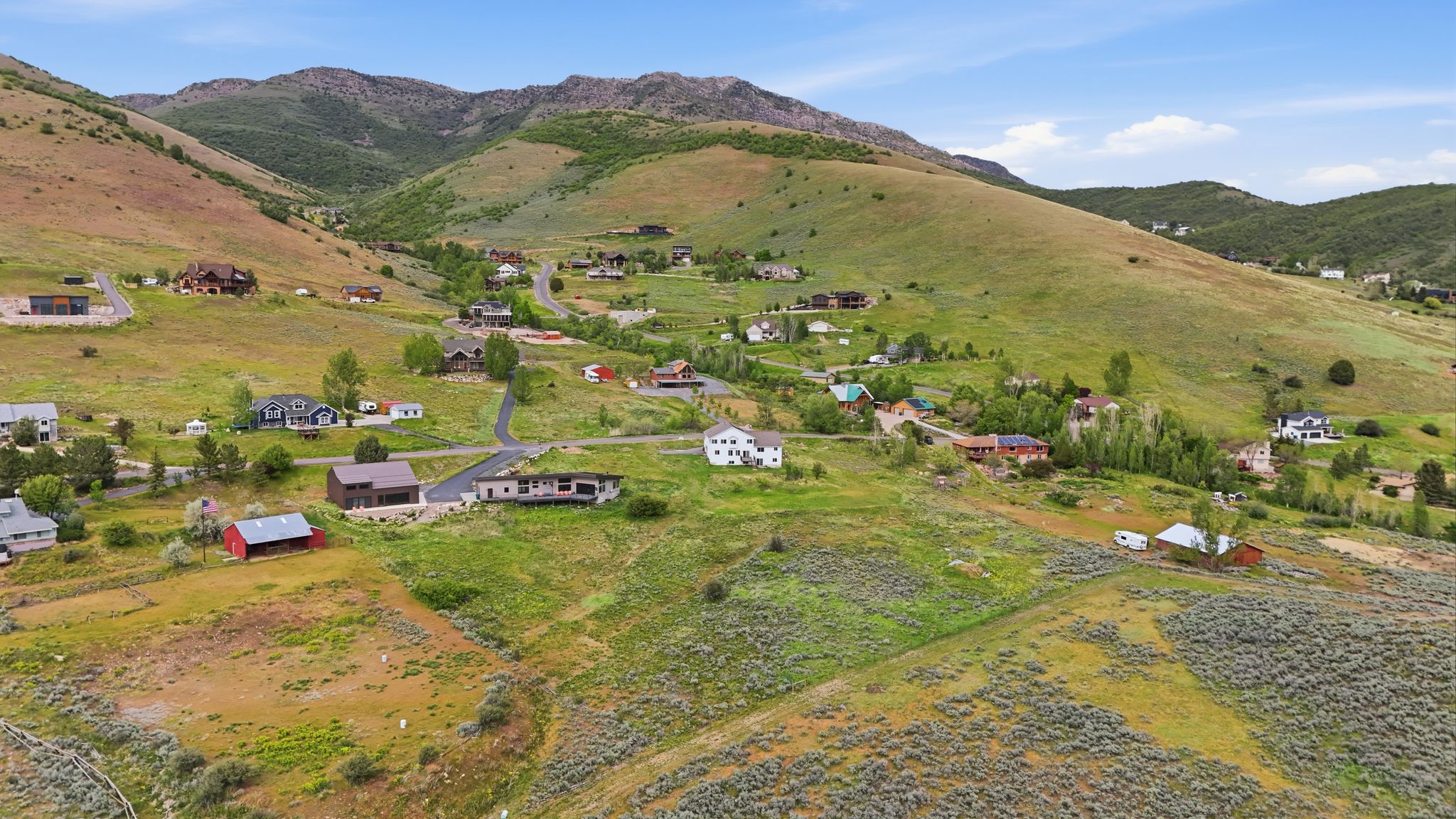 Expansive mountain valley setting featuring scattered residential properties, paved roads, and varied terrain