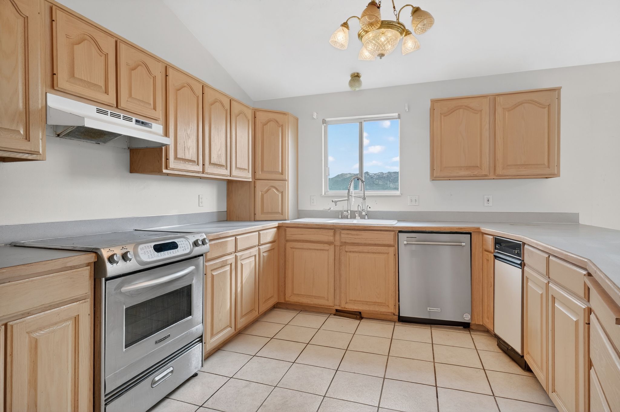 Kitchen featuring wood-finish cabinetry, stainless steel range and dishwasher, and a window above the sink