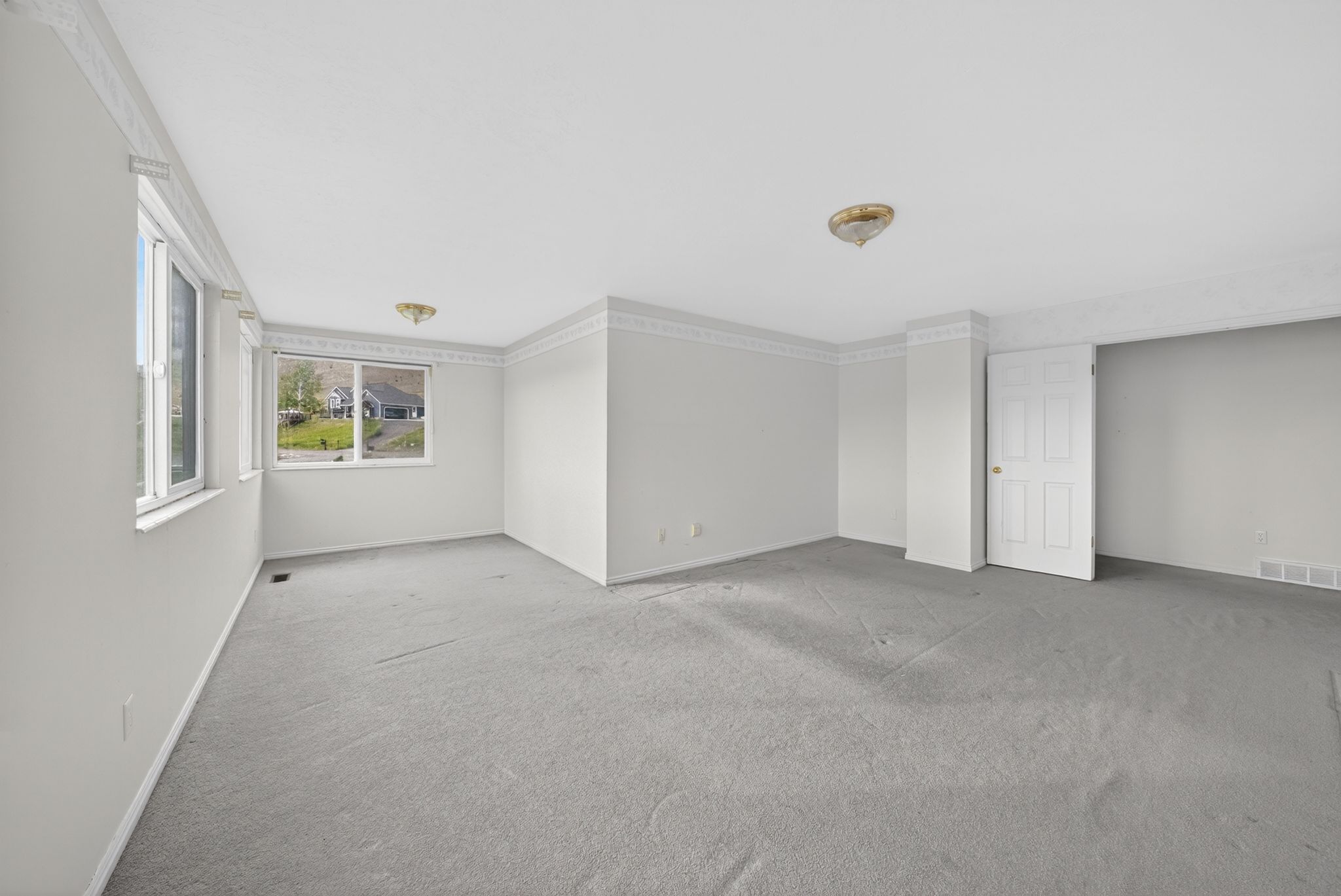 Spacious room with light gray carpeting and white walls