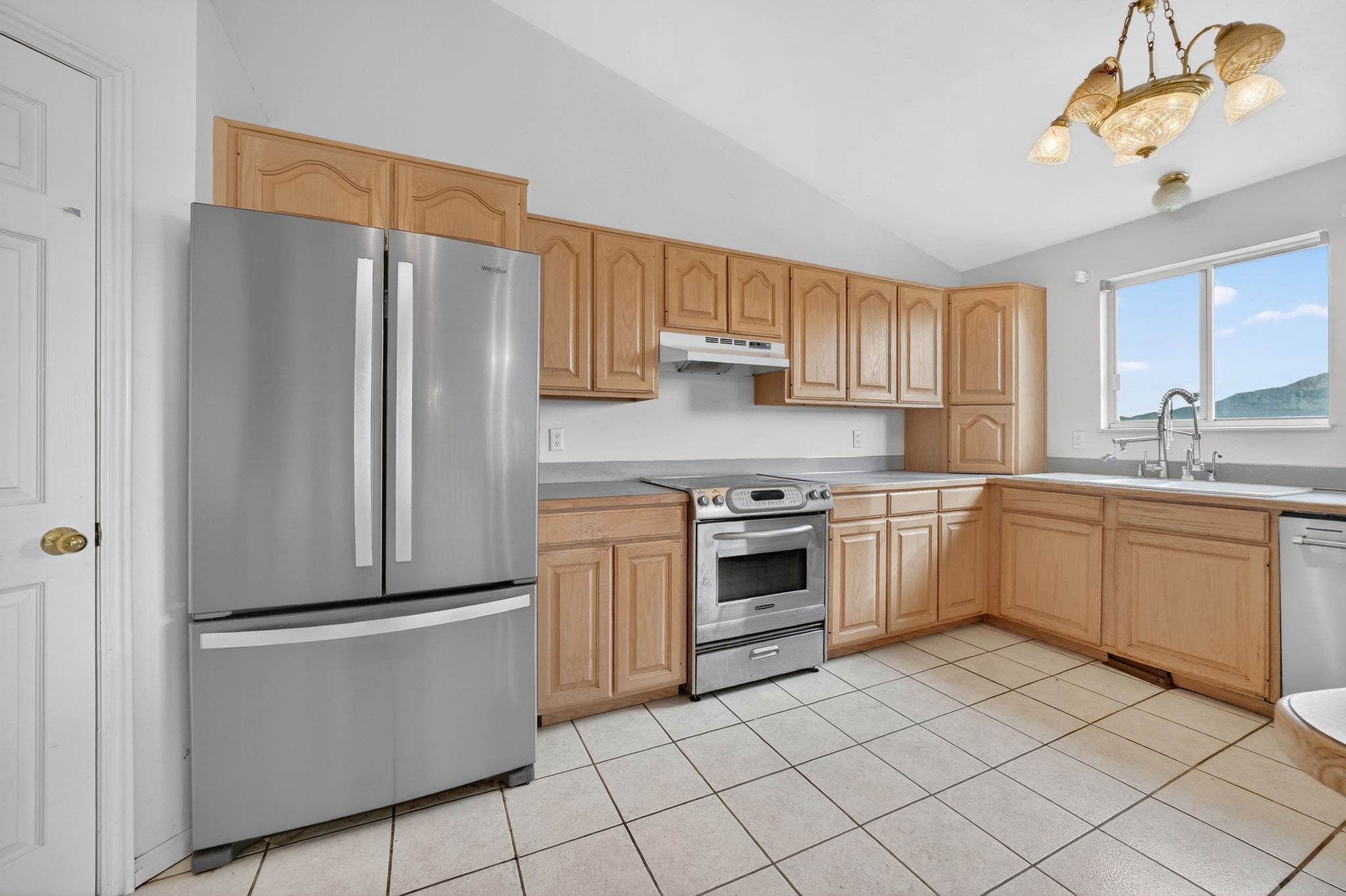 Kitchen featuring light wood cabinetry, stainless steel appliances, and tile flooring