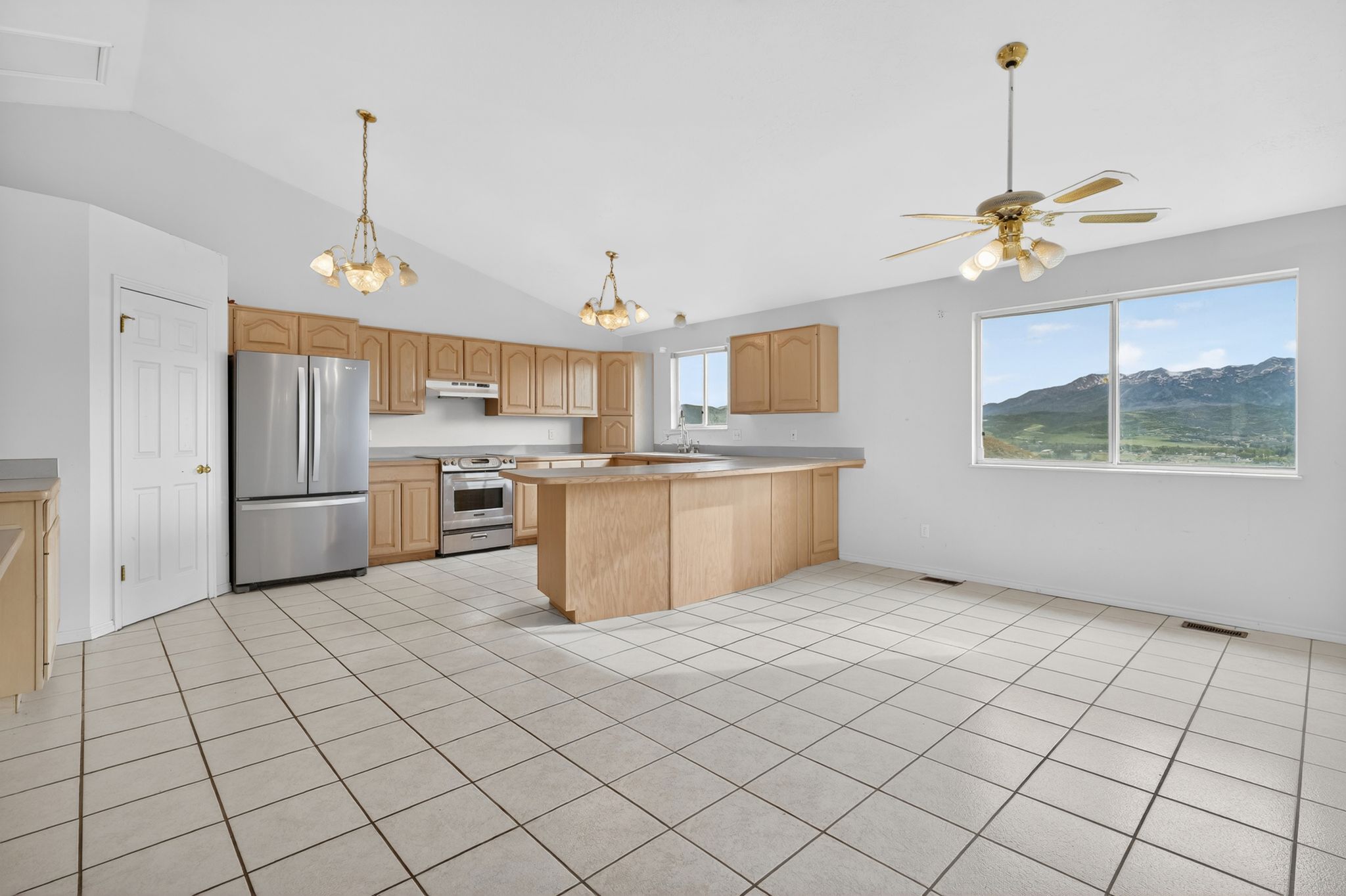 Kitchen featuring light wood-finish cabinetry, stainless steel appliances, and a central island with an extended counter