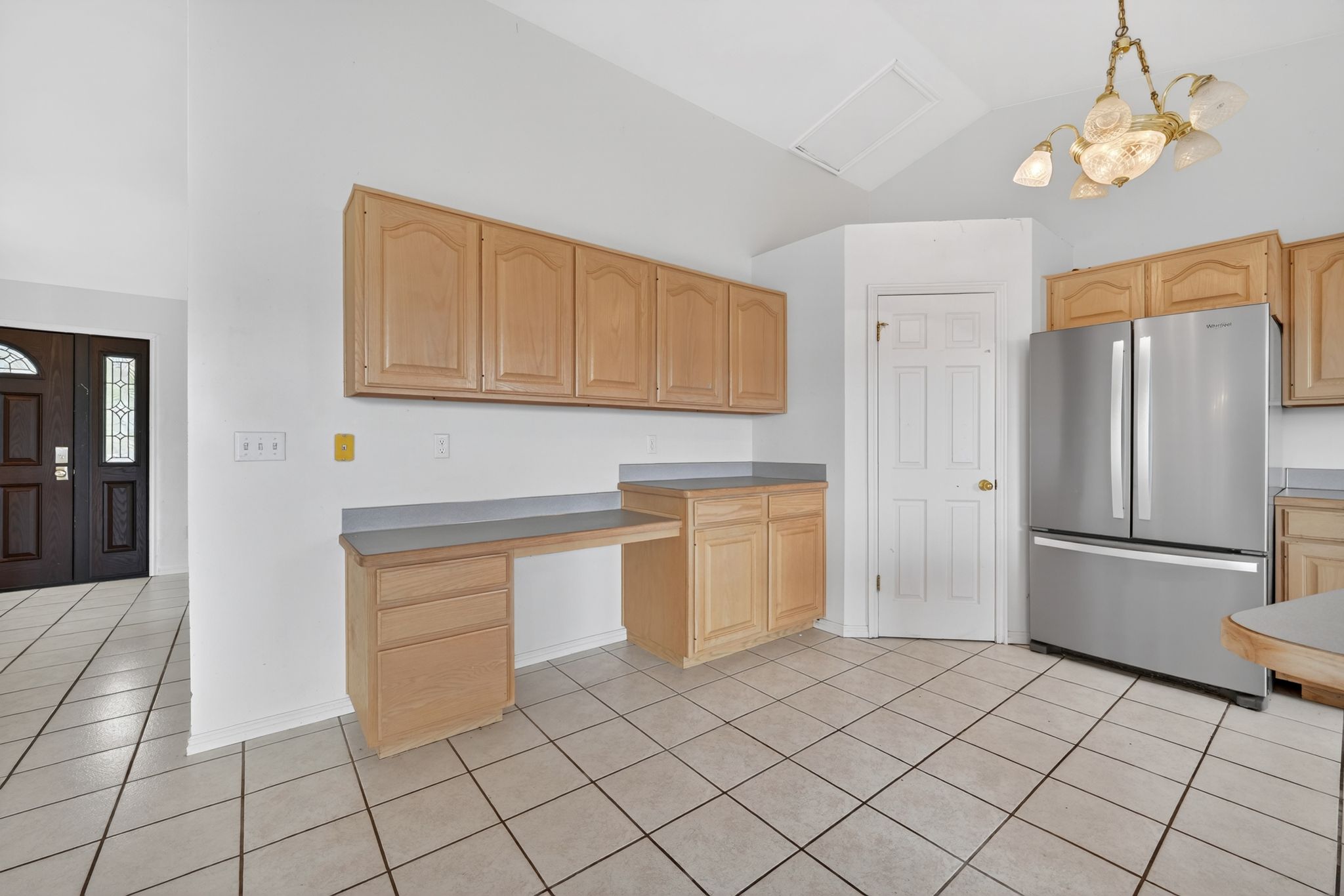 Kitchen area featuring light wood cabinetry, a built-in desk, and light gray countertops