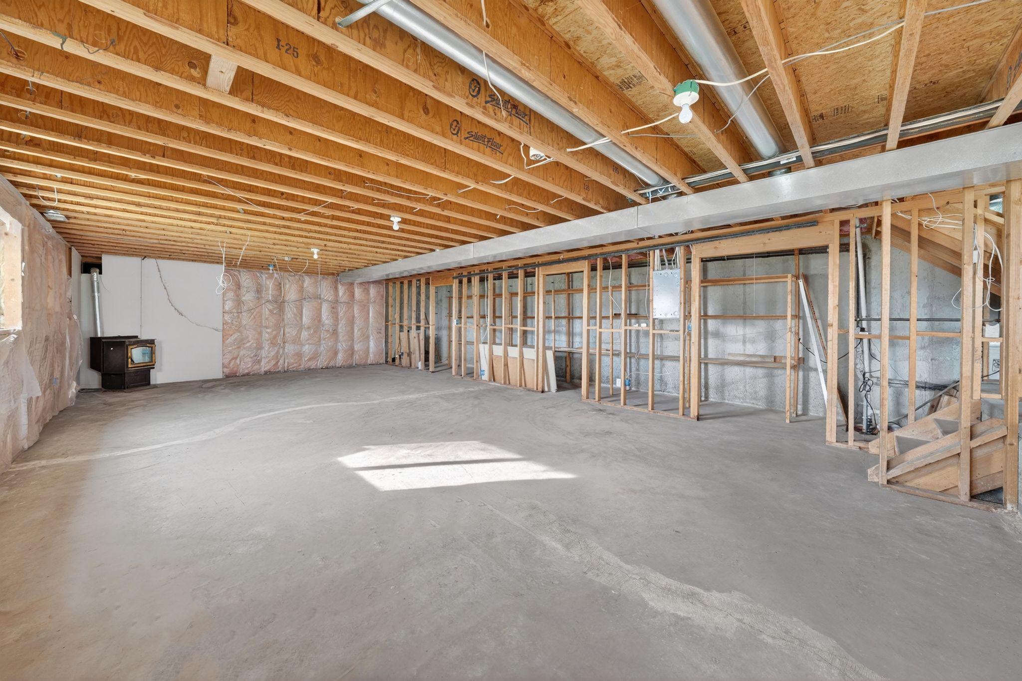Unfinished basement featuring exposed wood joists, concrete flooring, and partial wall framing