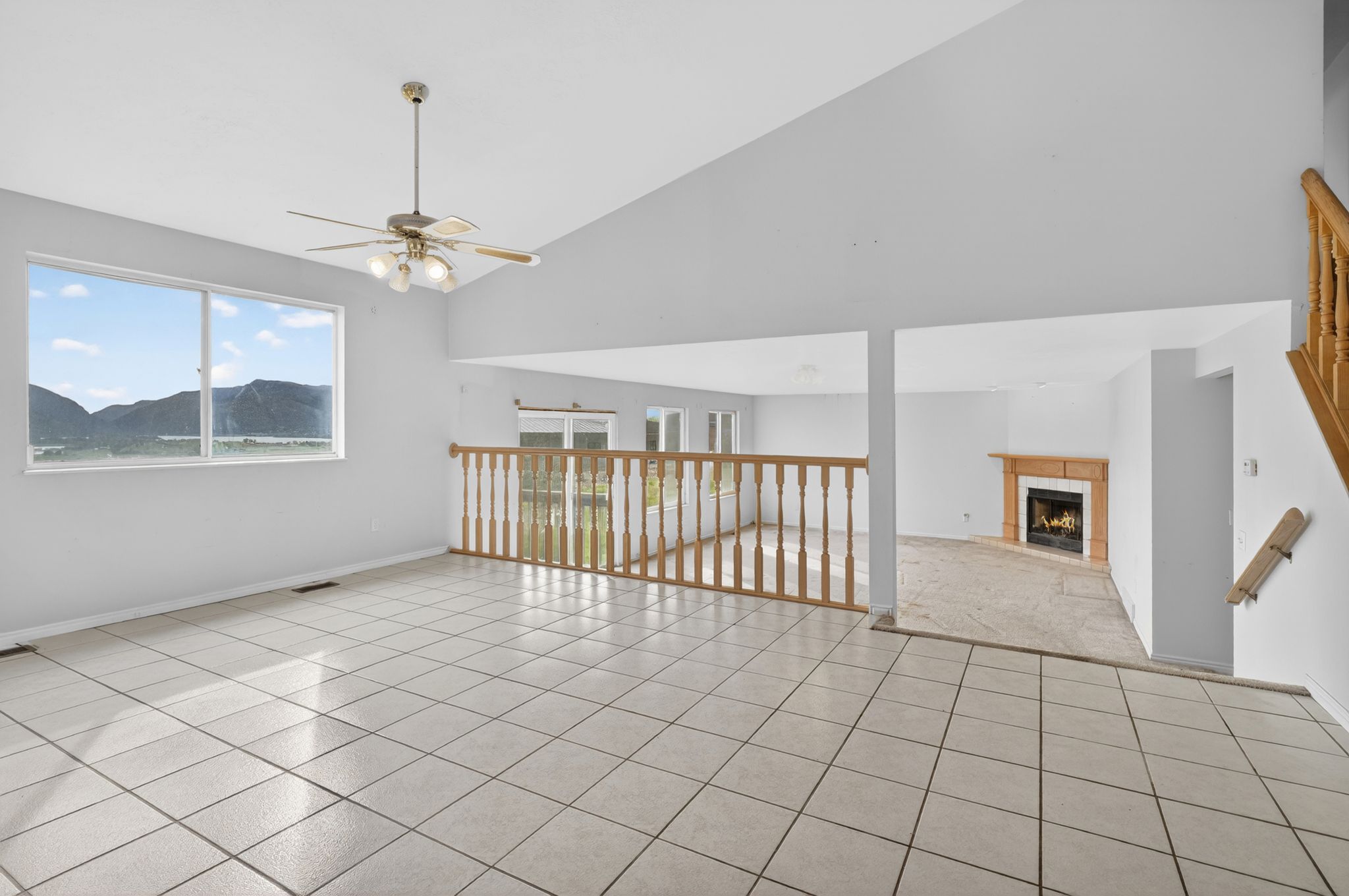 Open-concept living area featuring a vaulted ceiling and a ceiling fan