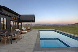 Expansive outdoor living area featuring a rectangular pool with an integrated spa