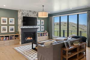 Living area featuring extensive window panels, a built-in fireplace with a stone surround, and wood-finish flooring