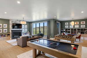 Spacious living area featuring light wood-finish flooring, recessed lighting, and a fireplace with a dark mantel and patterned surround