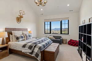 Vaulted ceiling bedroom featuring a large window with mountain scenery, recessed lighting, antler-style chandelier, and wood-finish headboard