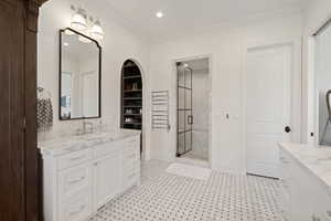 Bathroom featuring a marble-top vanity with white shaker cabinetry, a walk-in shower with a grid-patterned glass door, and black and white patterned floor tiling