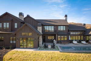Expansive rear elevation featuring extensive glass doors, multiple stone chimneys, and a dark wood-paneled exterior