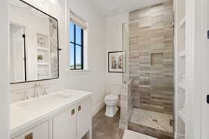 Bathroom featuring a glass-enclosed shower with horizontal tile, a white vanity with an integrated sink, a rectangular framed mirror, and a window with dark trim