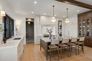 Gourmet kitchen featuring a large central island with seating, integrated appliances, wood-finish flooring, white shaker cabinetry, and dark-paneled windows