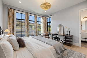 Spacious room featuring multiple large gridded windows, a decorative gold-toned light fixture, light wood-finish flooring, and light gray wall paint