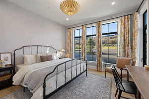 Light-filled room featuring large windows with black grilles, wood-finish flooring, recessed lighting, and a decorative ceiling fixture