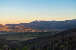 Expansive mountain landscape featuring a distant community nestled within a valley