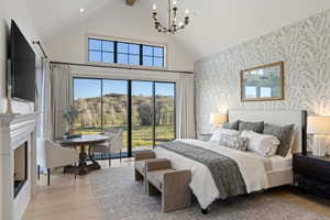 Vaulted ceiling featuring an exposed beam, a fireplace with a stone hearth and carved mantel, floor-to-ceiling sliding glass doors, and light wood-finish flooring