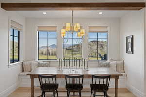 Dining area featuring a built-in bench, wood-finish flooring, exposed ceiling beam, and multiple windows with outdoor scenery