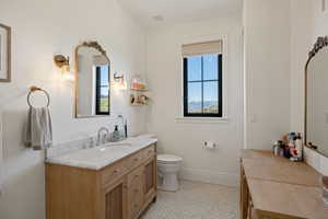 Bathroom featuring a light wood-finish vanity with a stone countertop, an undermount sink, and polished chrome fixtures