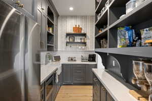 Gourmet pantry featuring full-height open shelving, extensive countertop space, integrated sink, and wood-finish flooring