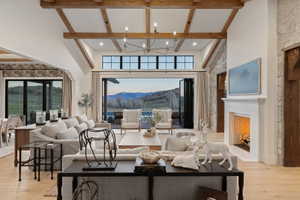 Spacious living area featuring exposed beam ceilings, a stone accent wall, and a white mantle fireplace with herringbone-patterned firebox