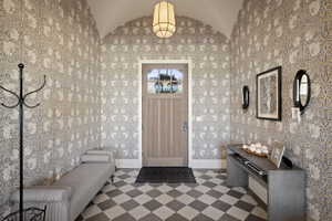 Entryway featuring arched ceilings and patterned wallpaper