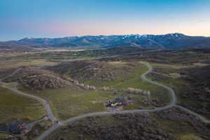 Expansive rural landscape featuring winding roads and a custom residence with a dark roof